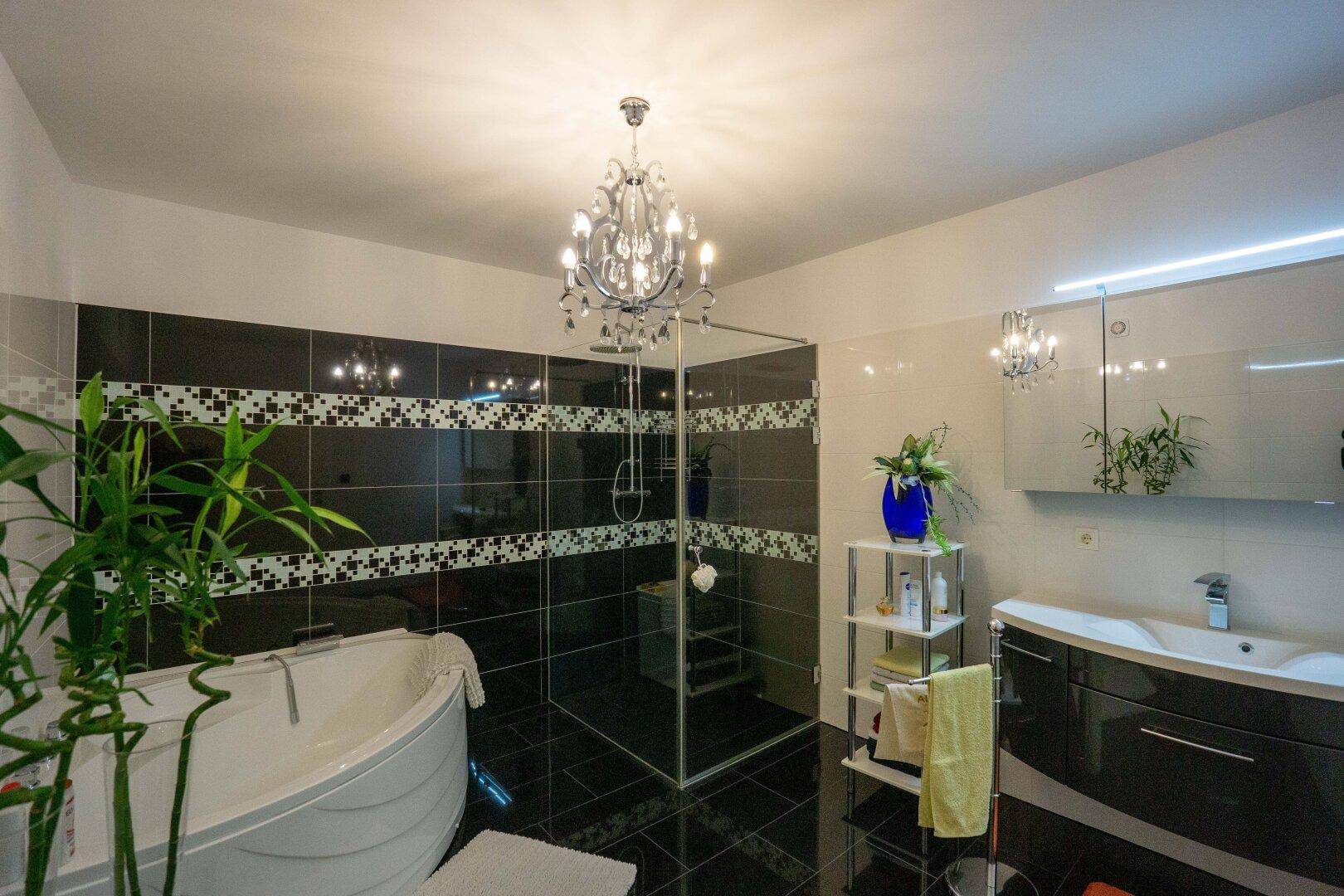 Modernes Badezimmer mit Badewanne, ebenerdiger Dusche und eleganten schwarzen Fliesen.