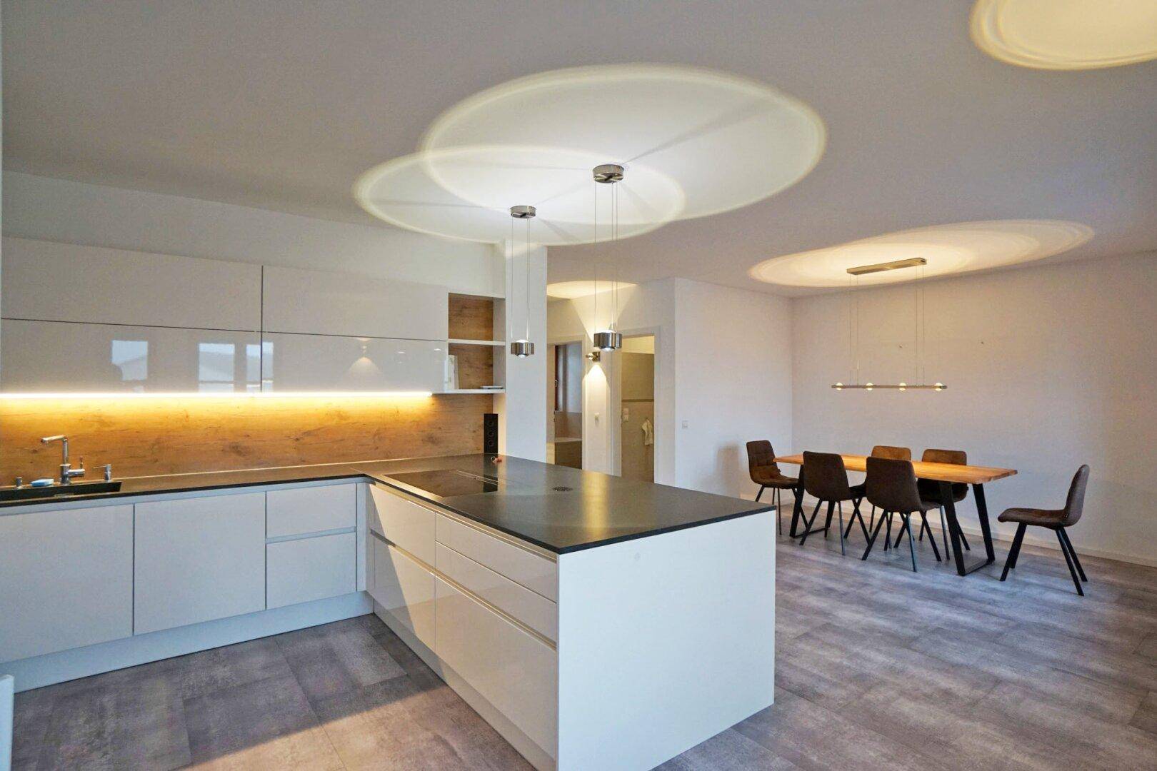 Offener Wohn- und Essbereich mit moderner Küche, Esstisch und stilvoller Beleuchtung.