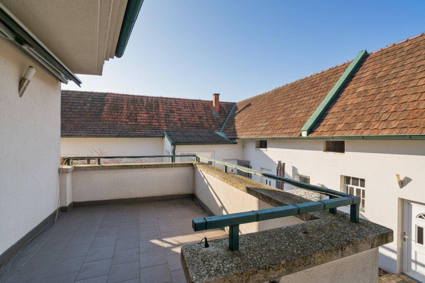 Geräumige Dachterrasse mit Fliesenboden und Blick auf die umliegenden Dächer.