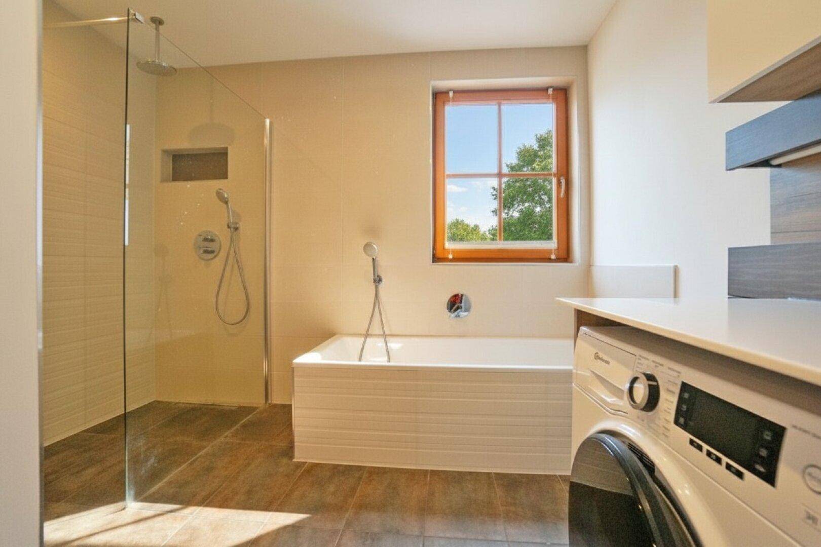 Modernes Badezimmer mit begehbarer Dusche, Badewanne und Waschmaschine.