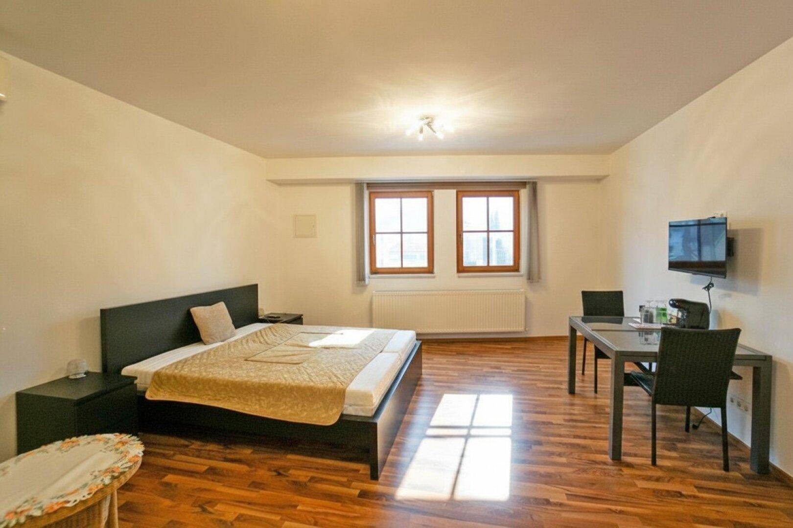 Geräumiges Schlafzimmer mit Holzboden, Doppelbett und kleinem Essbereich.