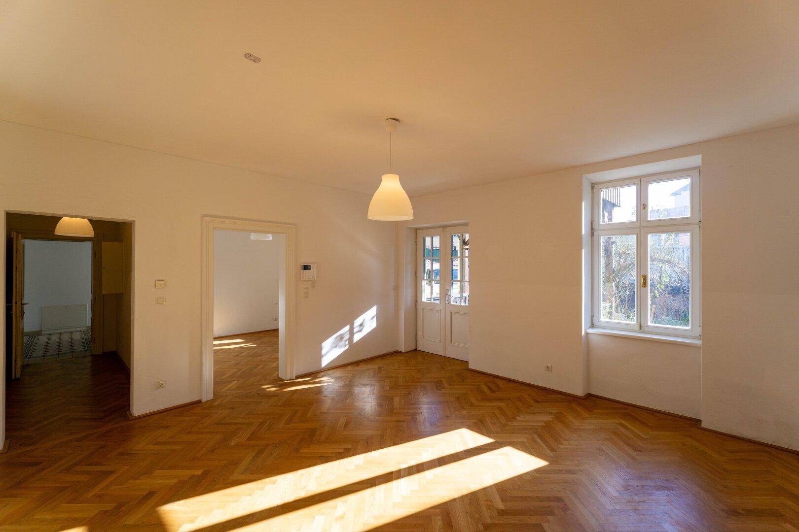 Leerer, heller Raum mit Fischgrätparkett und viel natürlichem Licht, bereit zur individuellen Gestaltung.