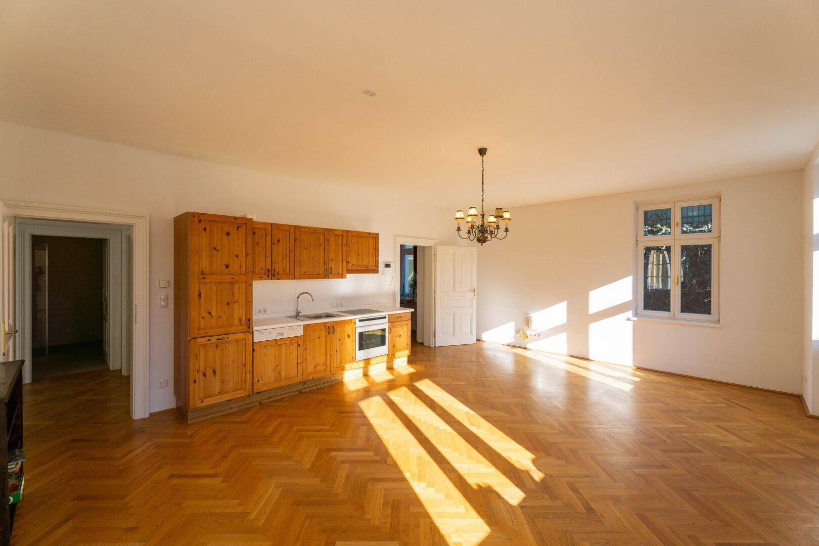 Heller Raum mit Parkettboden und einer einfachen Küchenzeile, ideal für ein Studio-Apartment.