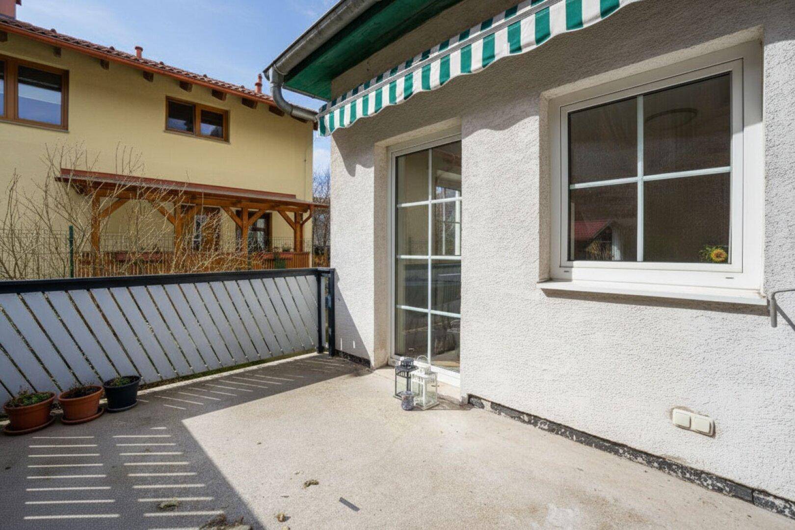 Kleine Terrasse mit Markise und Zugang zum Innenbereich, ideal für sonnige Tage.