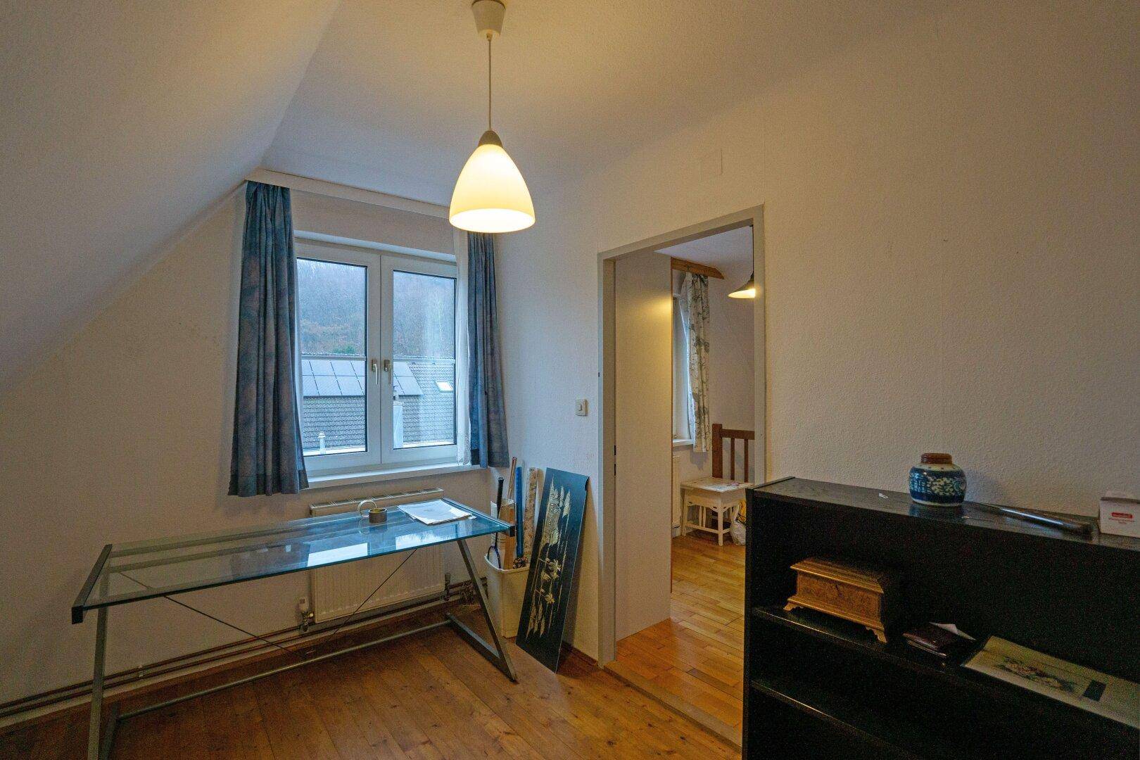 Kleines Arbeitszimmer mit Holzboden, Fenster und Blick auf die umliegende Landschaft.