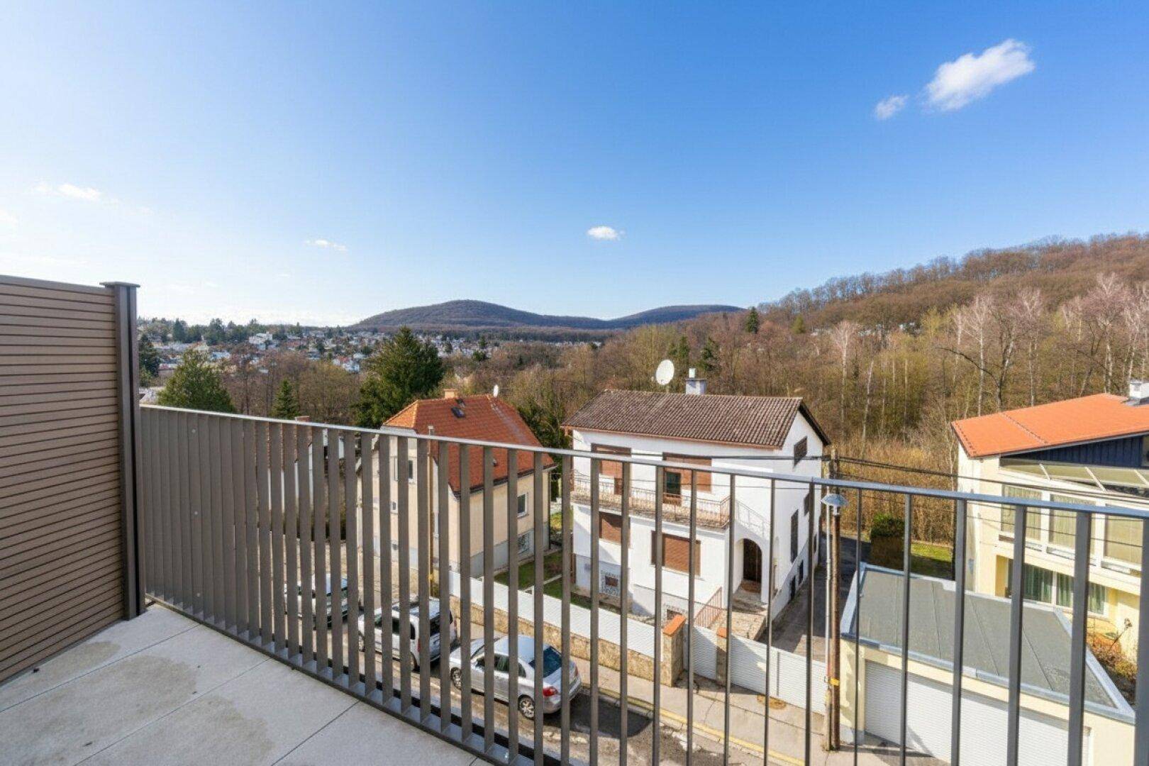 Balkon mit Metallgeländer und weitem Blick über eine grüne Hügellandschaft.