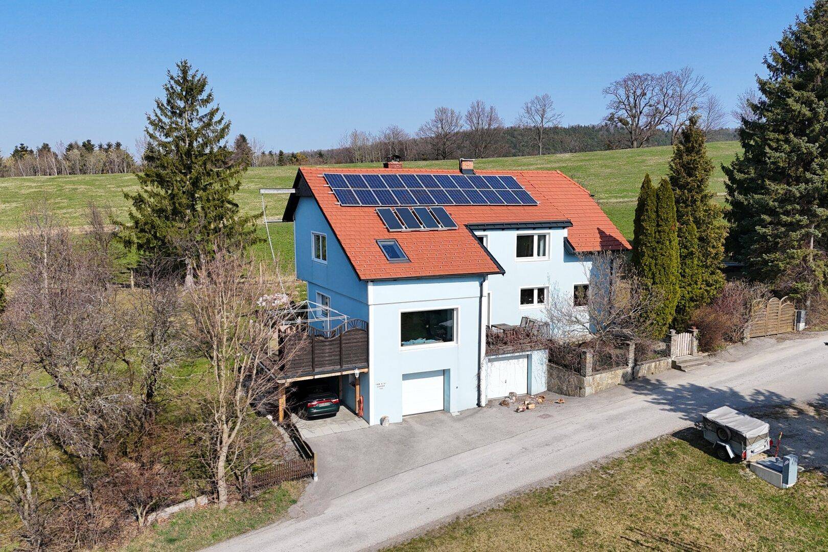 Modernes Haus mit Photovoltaikanlage auf dem roten Dach und integrierter Garage.