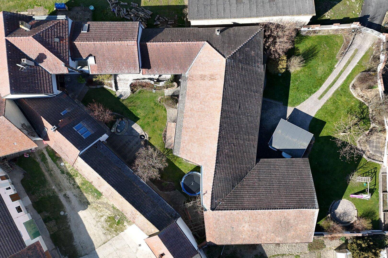 Draufsicht auf das Anwesen mit mehreren Gebäuden, Dächern und Gartenbereichen.