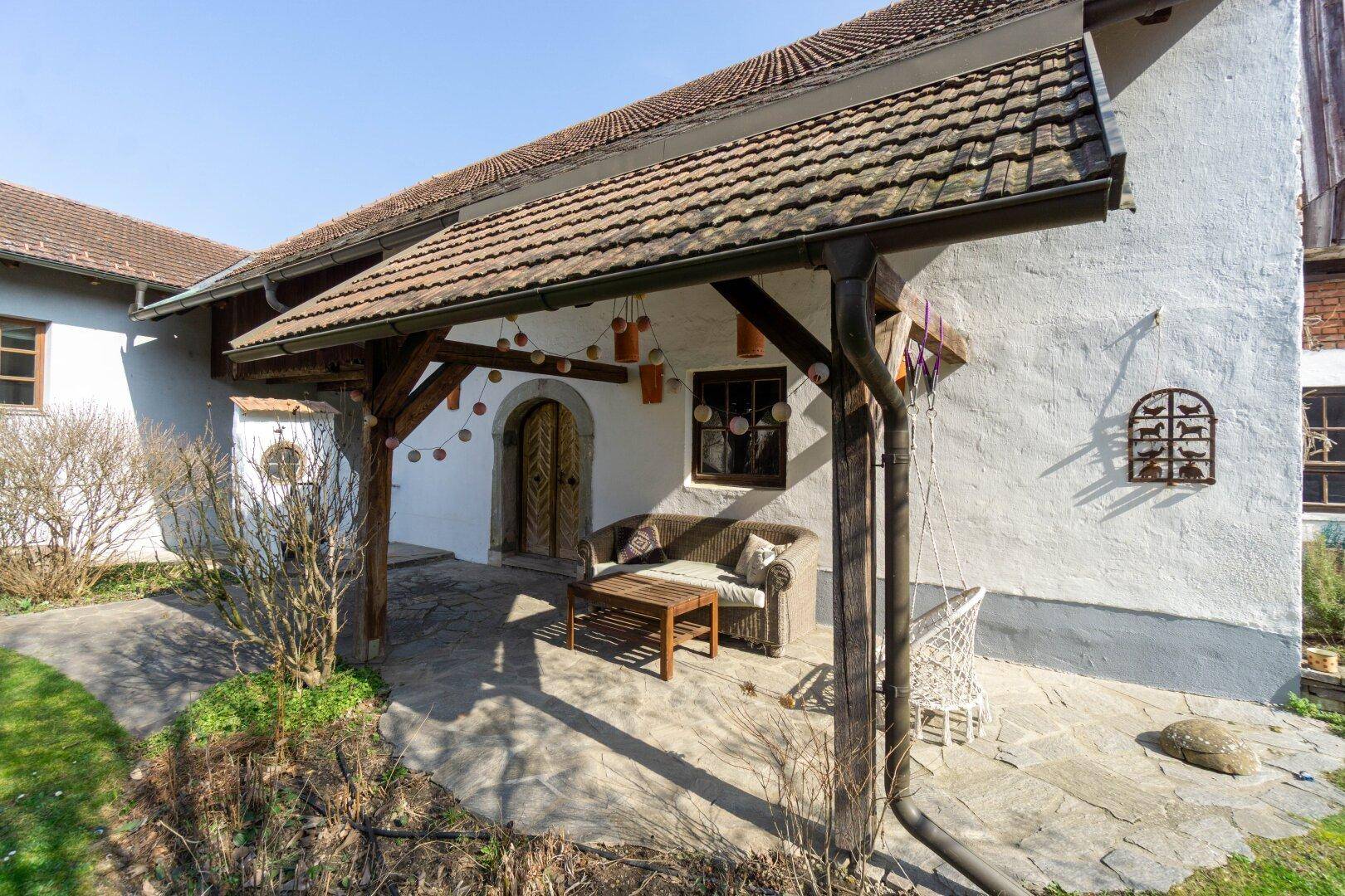 Überdachte Terrasse mit Sitzmöbeln und Holzbalken, ideal für entspannte Stunden im Freien.