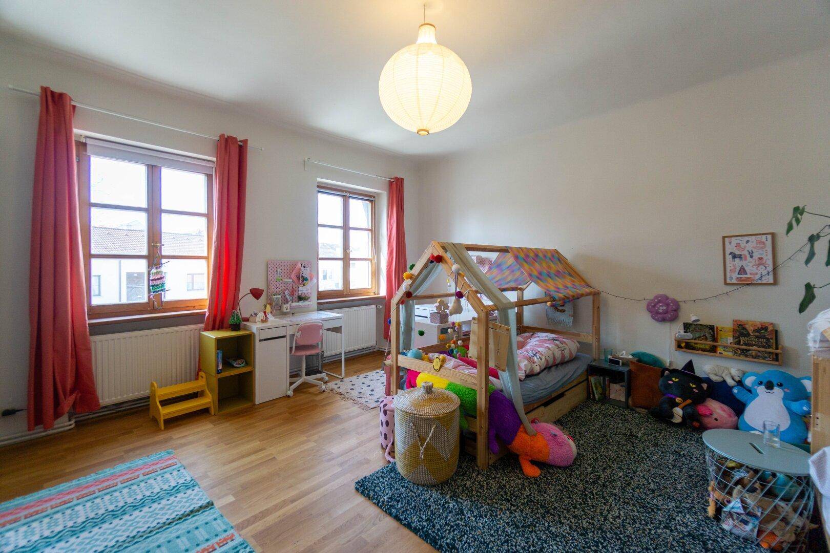 Kinderzimmer mit Holzboden, hellem Licht und farbenfroher Einrichtung.