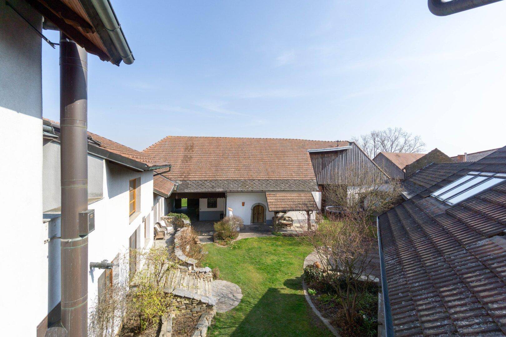 Blick von oben auf den Innenhof mit Rasenfläche und den Dächern der umliegenden Gebäude.