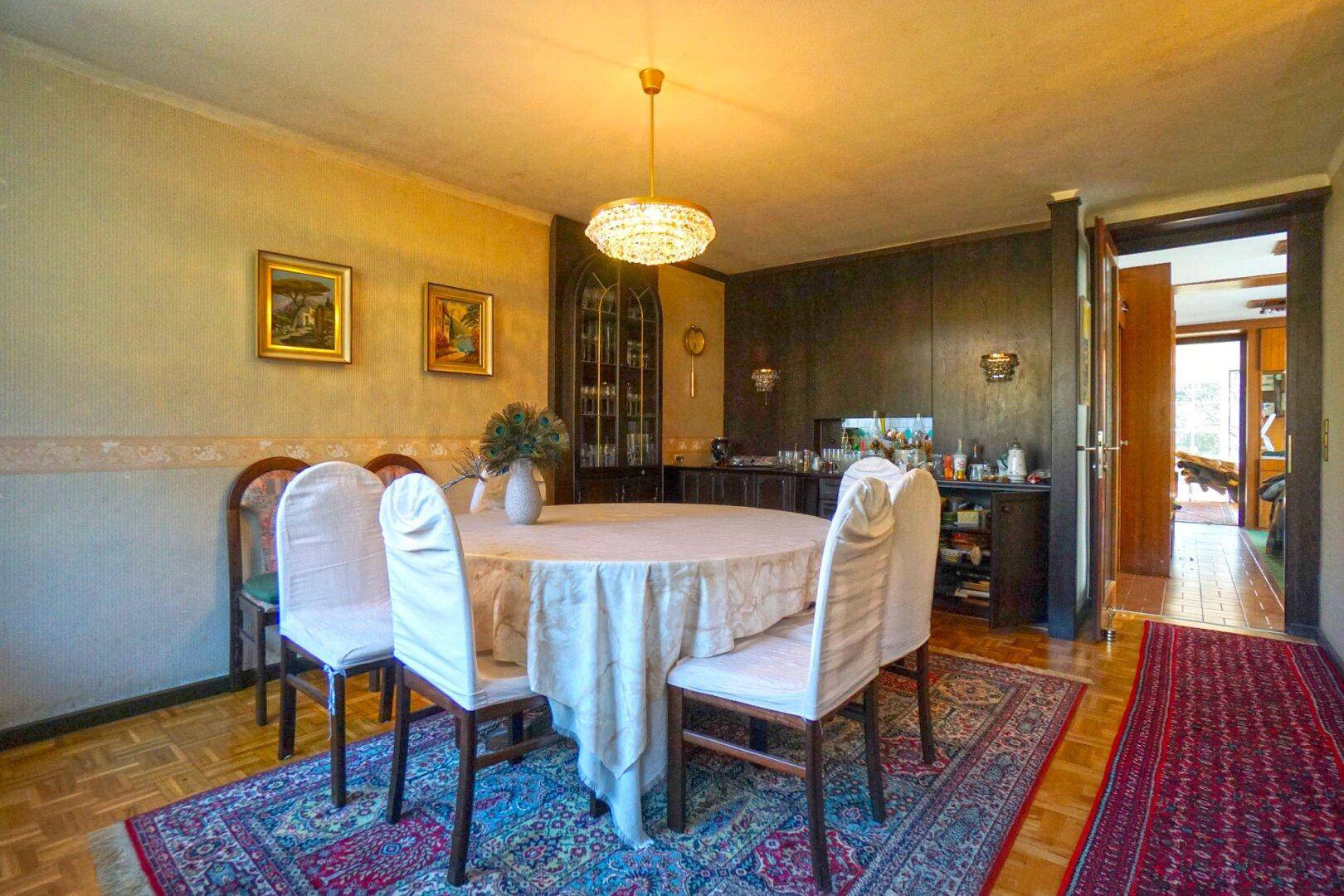 Gemütliches Esszimmer mit Holzboden, traditionellem Teppich und einem runden Esstisch.