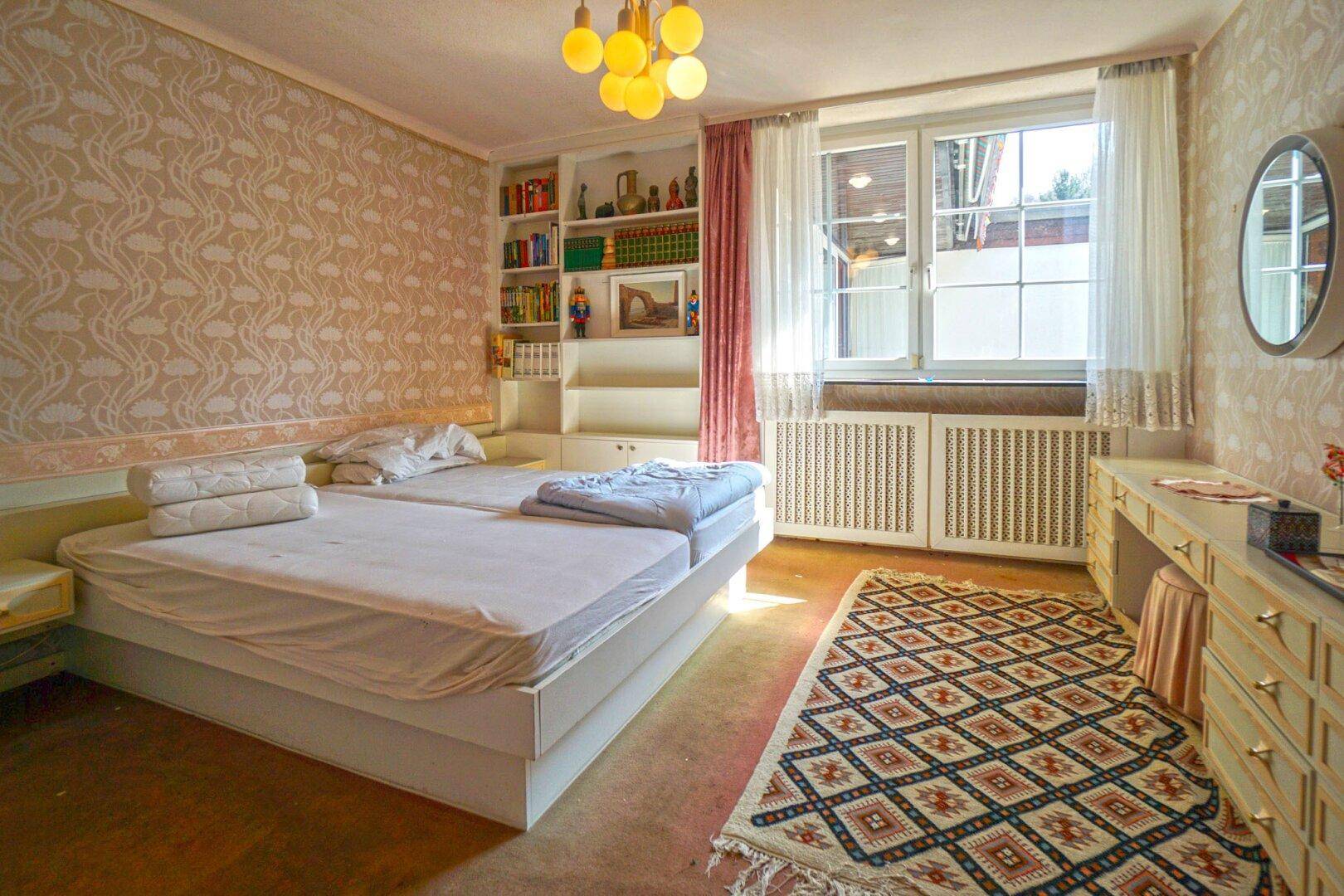 Schlafzimmer mit zwei Einzelbetten, Einbauregalen und Fenster mit Blick ins Grüne.