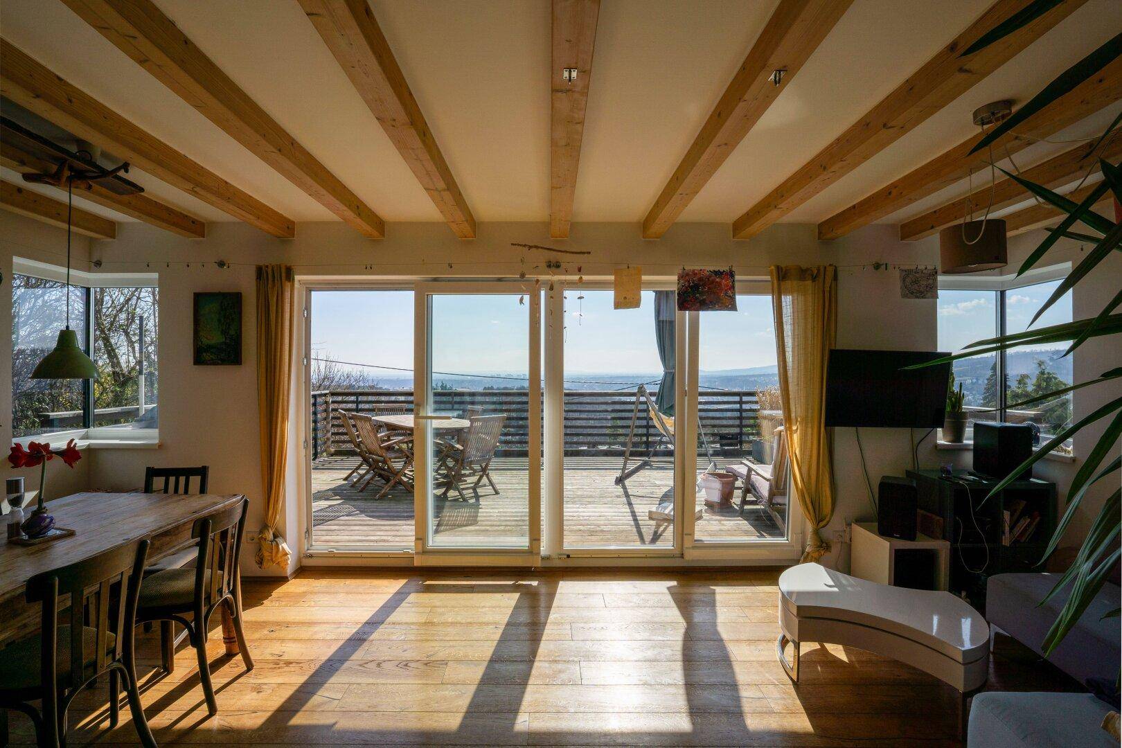 Lichtdurchfluteter Wohn- und Essbereich mit Holzbalkendecke und großen Schiebetüren zur Terrasse.