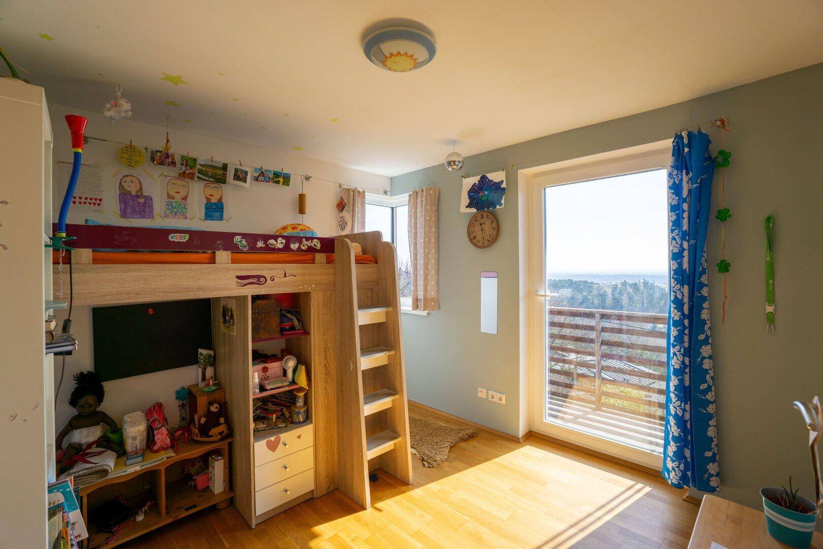 Kinderzimmer mit Hochbett, bunten Dekorationen und Zugang zu einem Balkon mit schöner Aussicht.