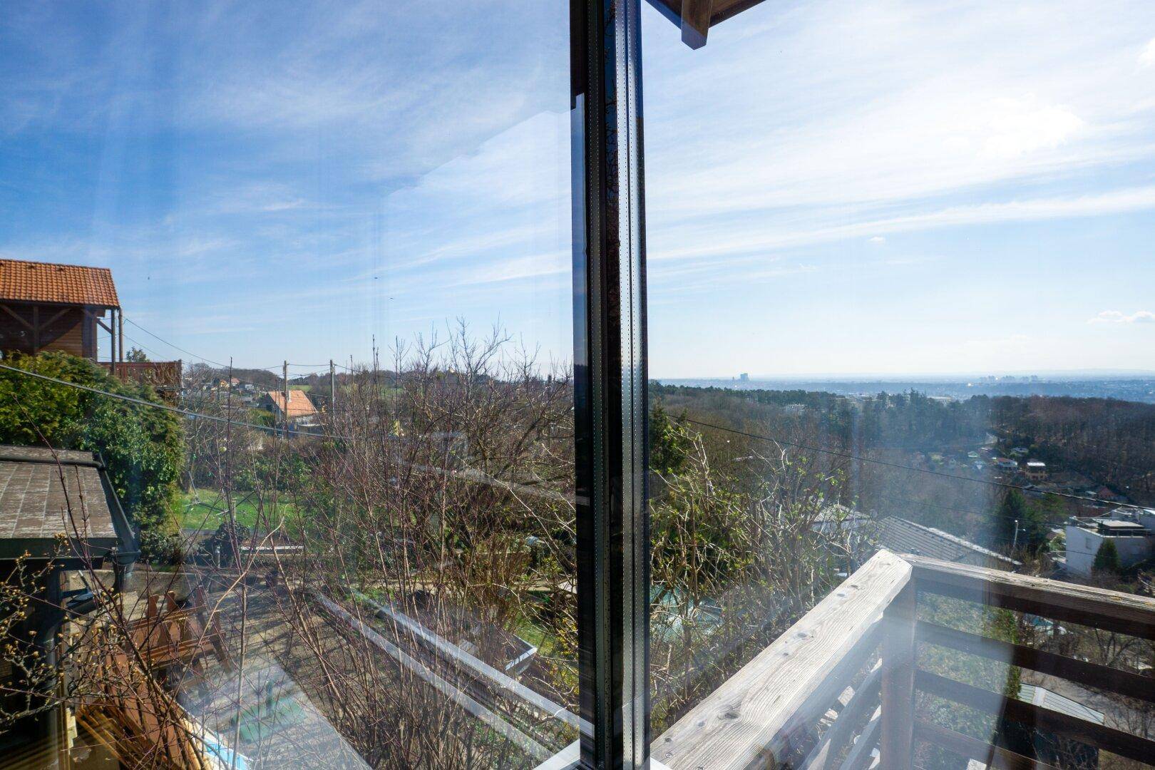 Blick aus dem Fenster auf die grüne Umgebung und die umliegende Landschaft unter blauem Himmel.