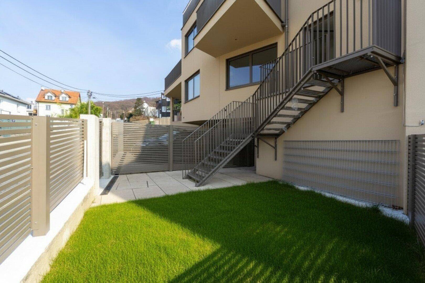 Kleiner privater Gartenbereich mit Rasenfläche und gepflastertem Zugang zum Gebäude.