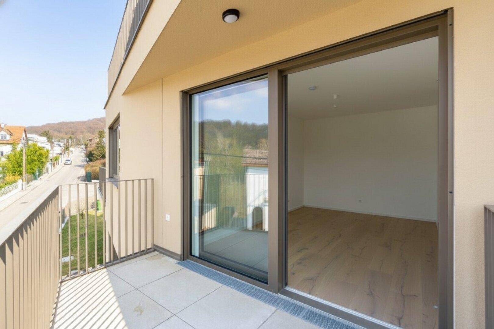 Geräumiger Balkon mit Fliesenboden und Blick auf die Straße und die umliegende Wohnbebauung.