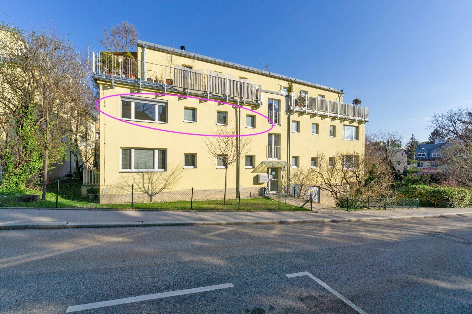 Gebäudefassade von der Straße aus gesehen mit mehreren Balkonen und Parkmöglichkeiten.