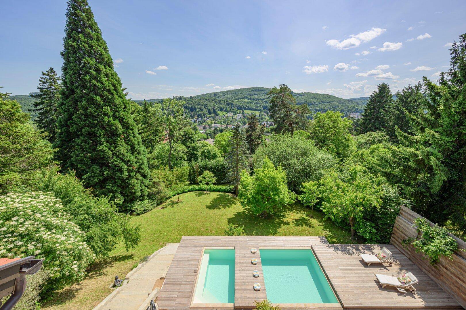 Entspannender Poolbereich mit Holzdeck und weitem Blick über die grüne Hügellandschaft.