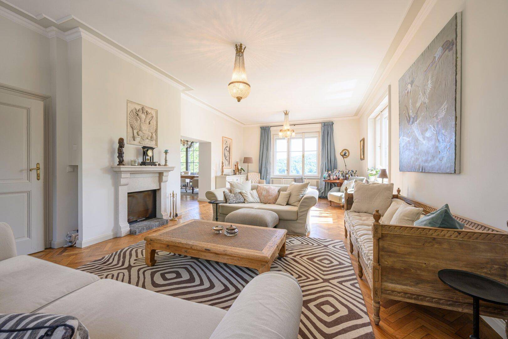 Geräumiges Wohnzimmer mit Kamin, eleganten Möbeln und Parkettboden, ideal zum Entspannen.