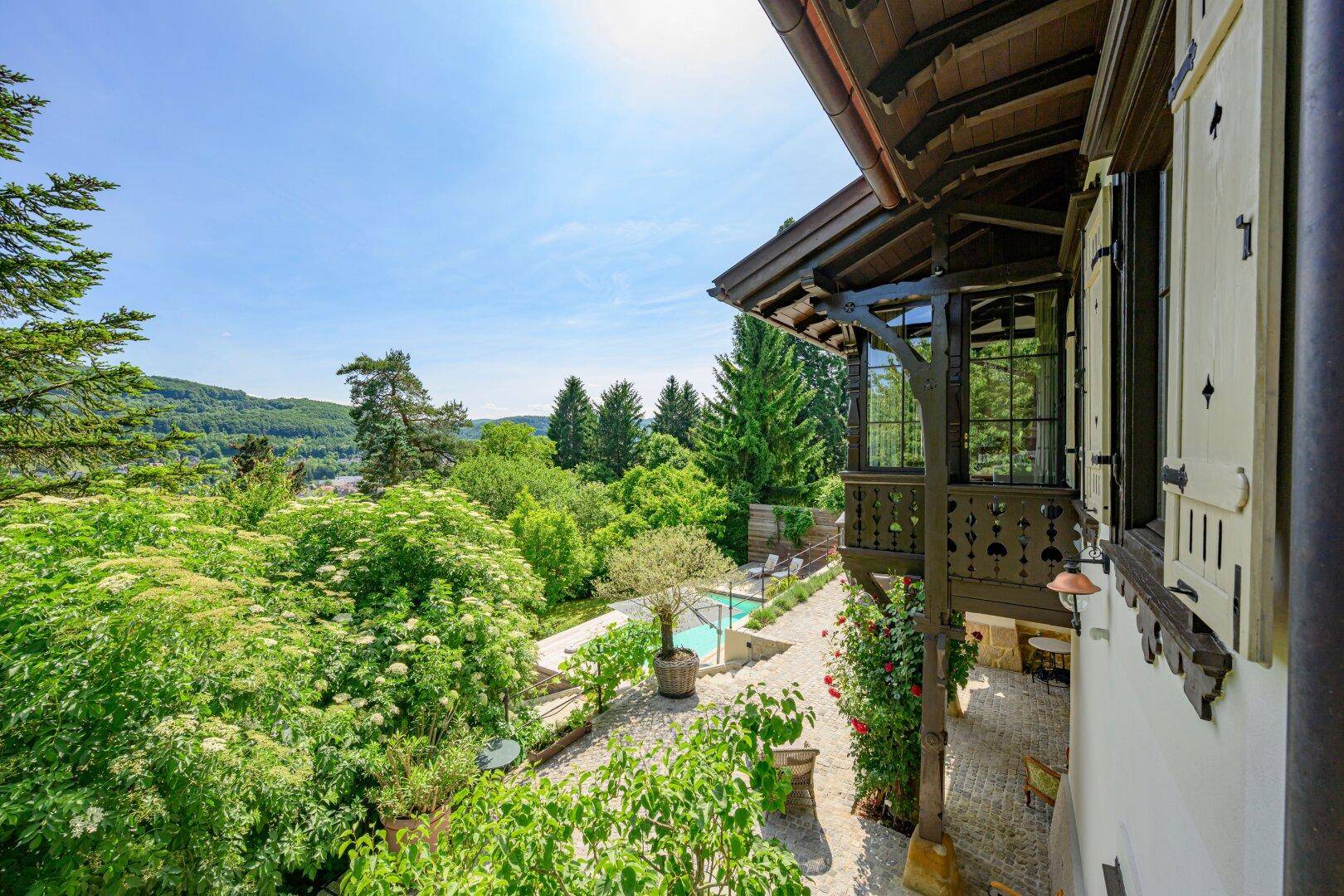 Malerischer Balkon mit Blick auf den gepflegten Garten, den Pool und die grüne Umgebung.