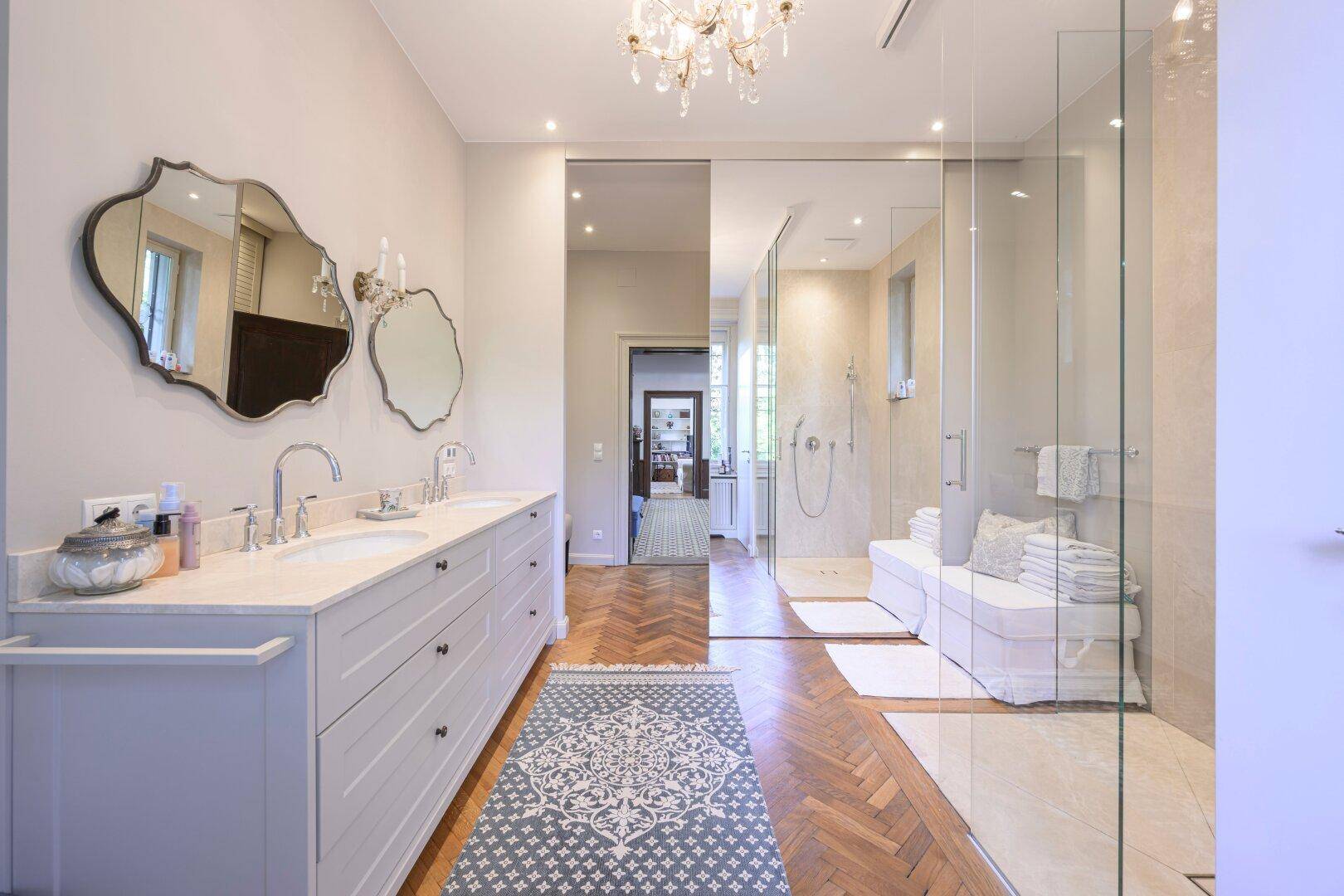 Modernes Badezimmer mit Doppelwaschbecken, großer begehbarer Dusche und Parkettboden.