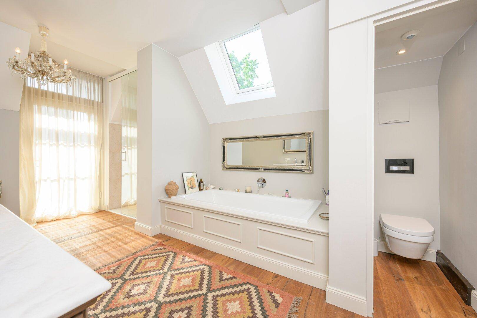 Helles Badezimmer mit Badewanne, Dachfenster und separatem WC-Bereich, bietet viel Tageslicht.