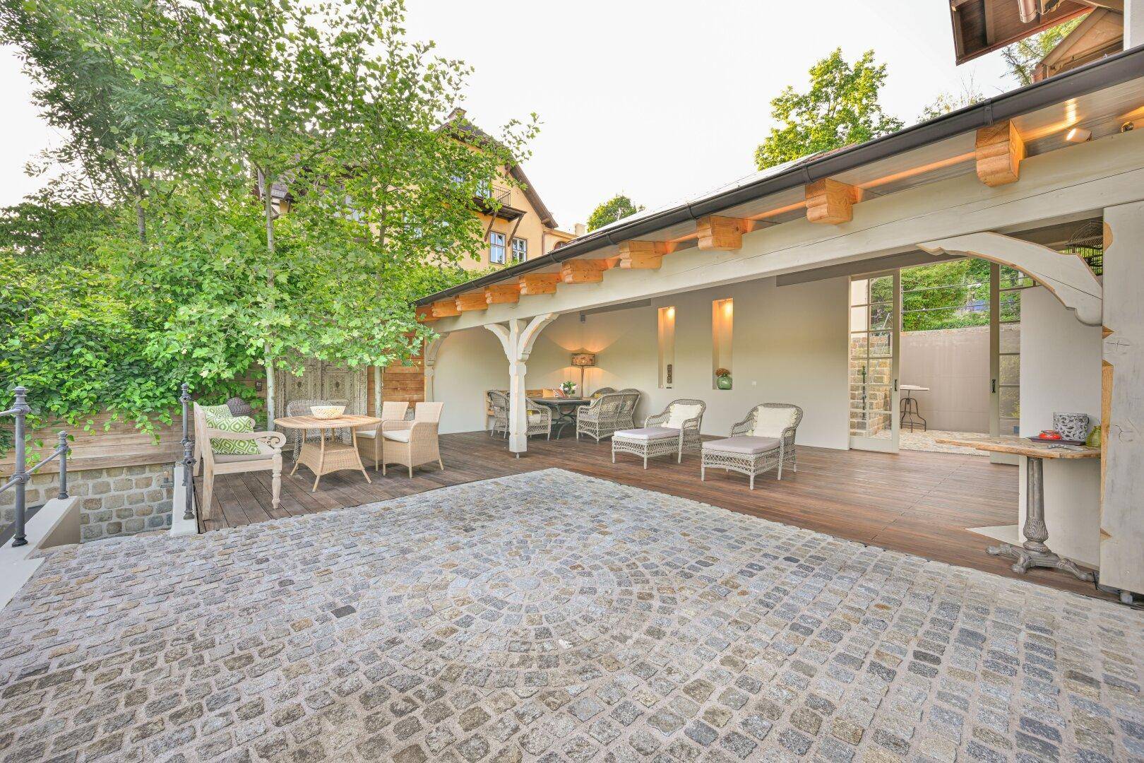 Überdachte Terrasse mit Holzboden und bequemen Sitzgelegenheiten, ideal für gesellige Stunden.
