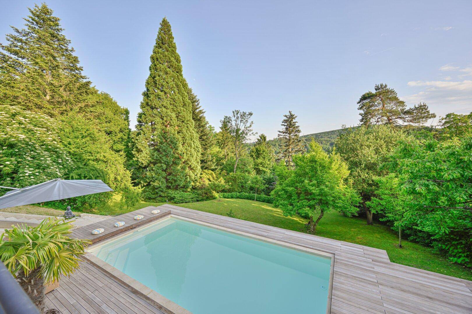 Einladender Poolbereich mit Holzdeck und weitem Blick auf die umliegende grüne Landschaft.