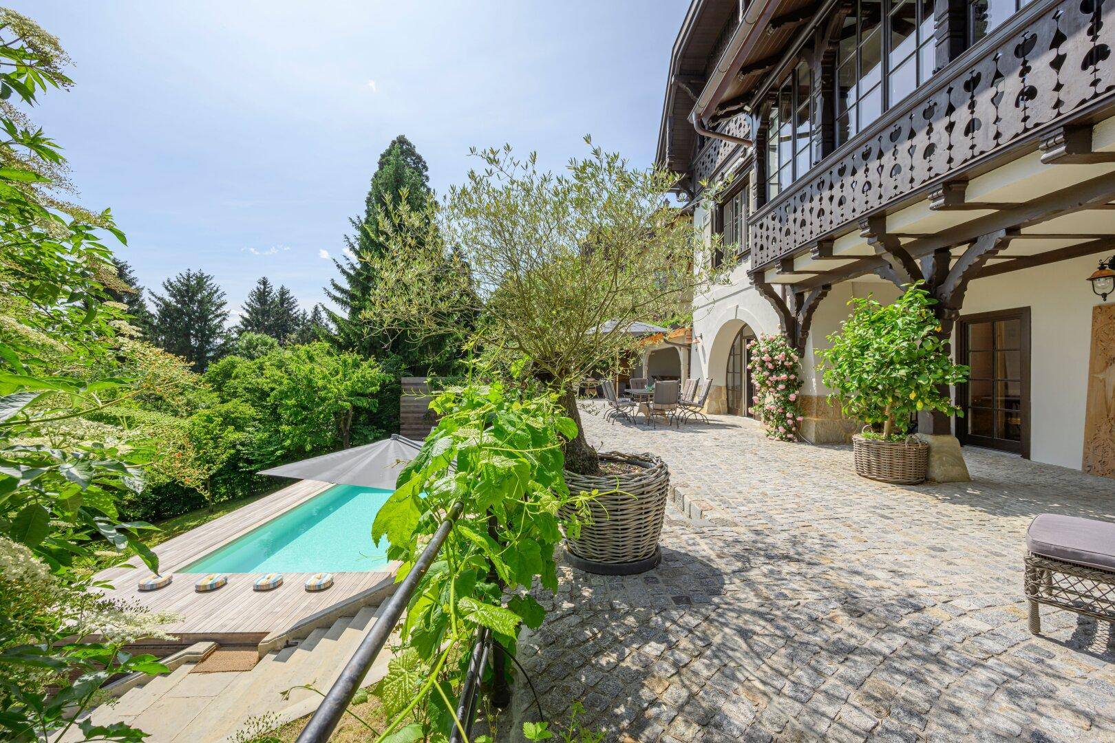 Gepflasterter Innenhof mit Blick auf den Pool und die Villa, umgeben von mediterranen Pflanzen.