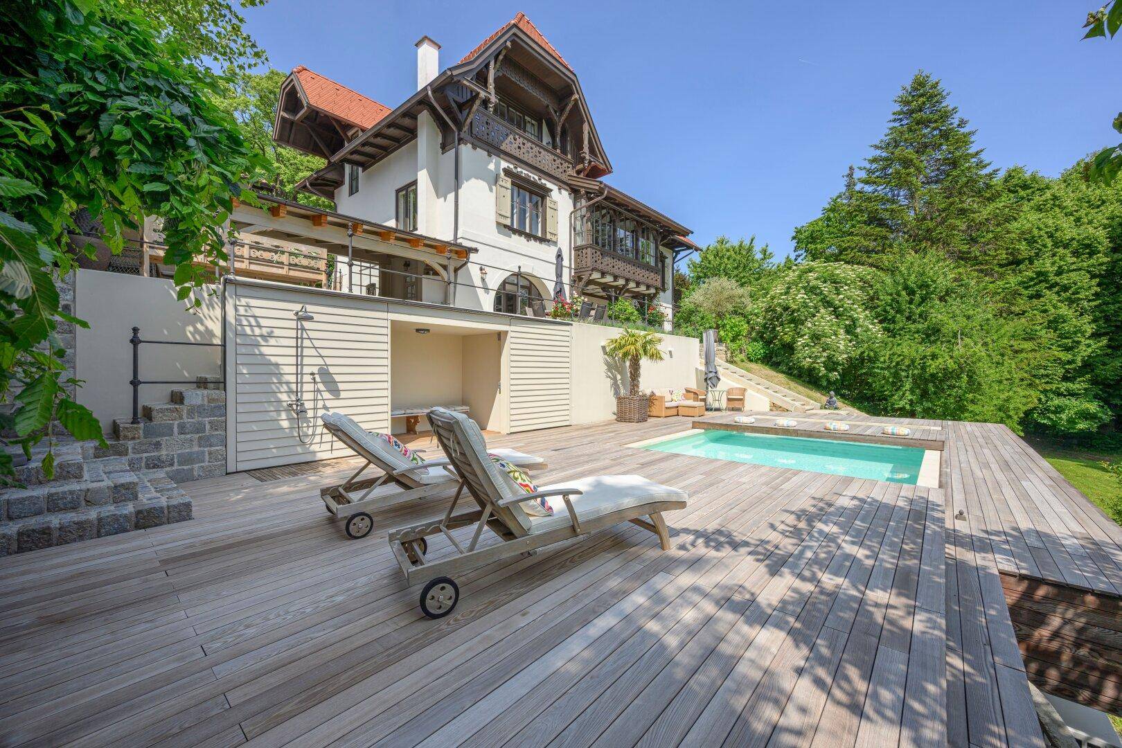 Sonniger Poolbereich mit Holzdeck und Liegestühlen, ideal zum Entspannen im Freien.