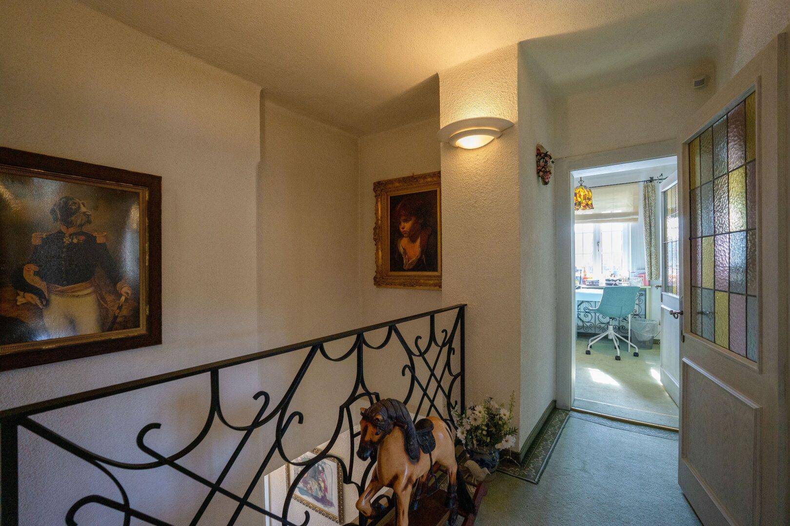 Heller Flur mit Kunstwerken an den Wänden und Blick in ein angrenzendes Arbeitszimmer.