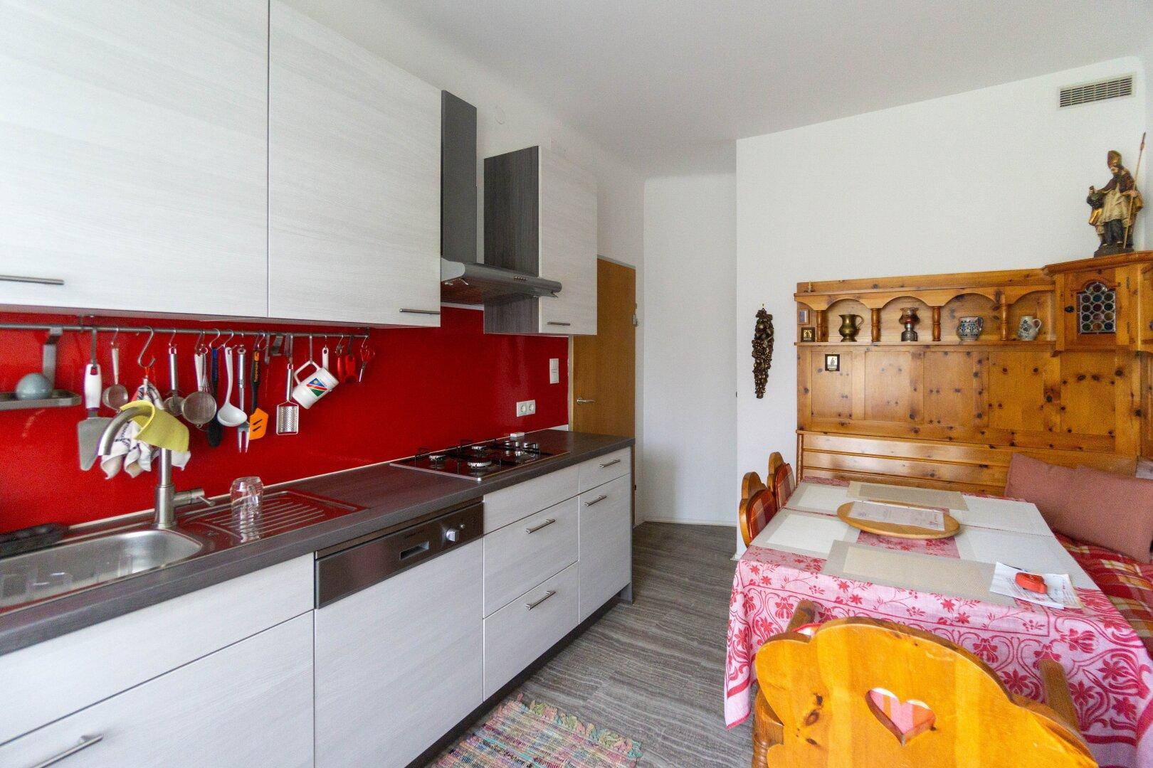 Moderne Einbauküche mit roter Rückwand und Essbereich im Landhausstil.
