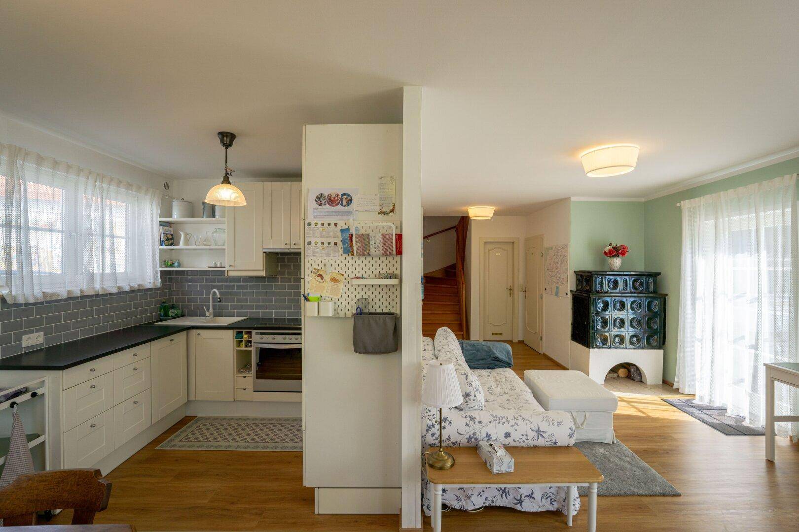 Halboffene Küche mit weißen Einbauschränken, Backofen und Holzboden.