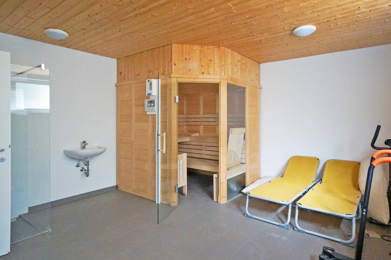 Wellnessbereich mit Sauna, Dusche und Liegestühlen, ideal zur Entspannung und Fitness.