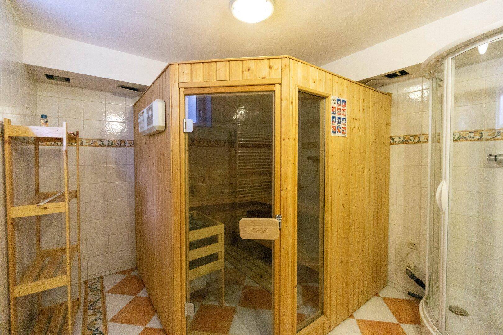 Wellnessbereich im Untergeschoss mit Sauna, Dusche und gefliestem Boden.