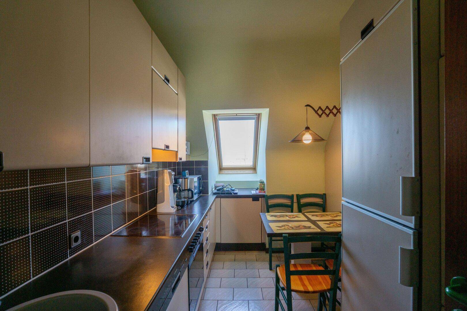 Gemütliche Küche mit Dachfenster, Einbauküche und kleinem Essbereich unter der Dachschräge.