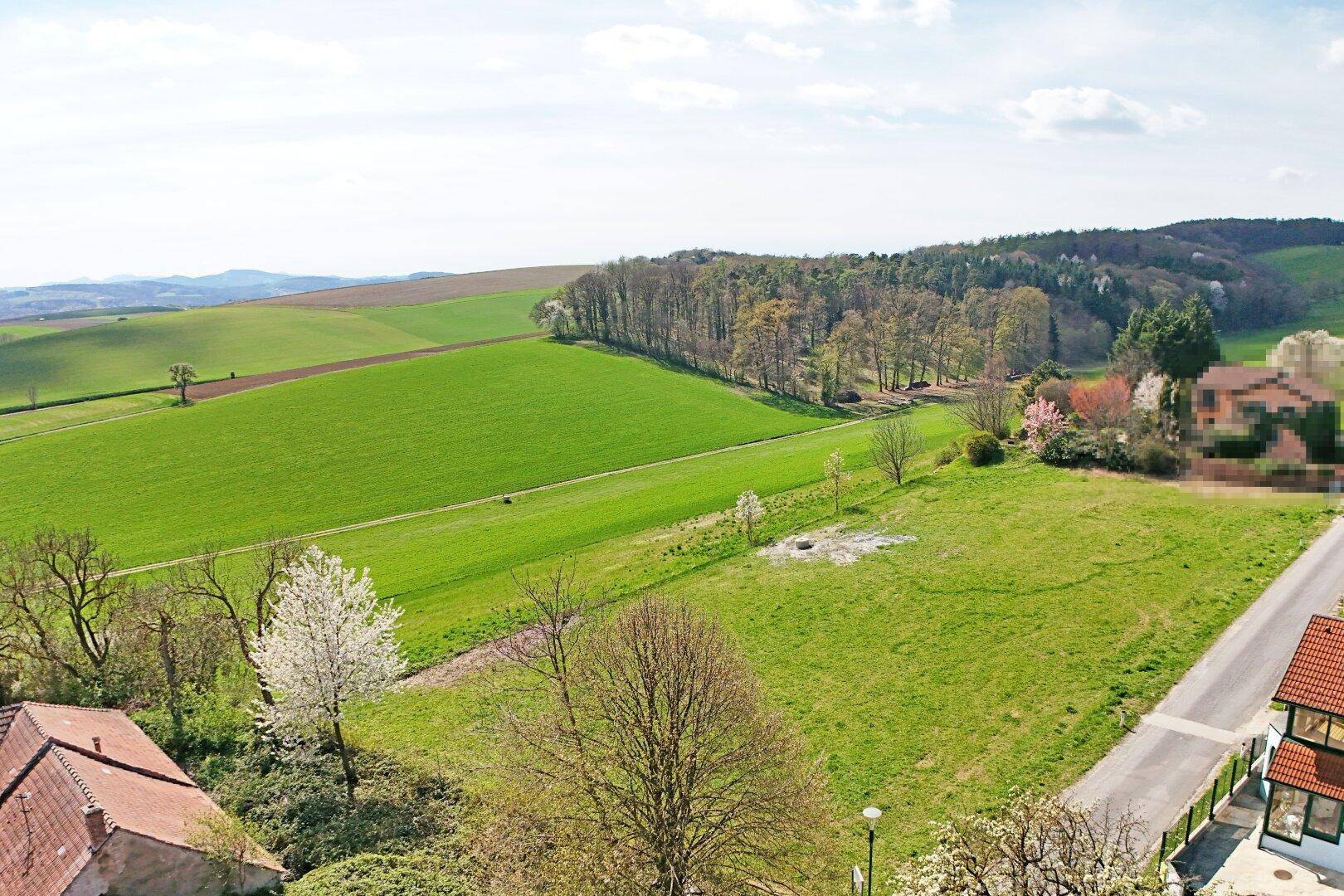 Weitläufige Landschaftsaufnahme mit grünen Feldern, Wäldern und einem Panoramablick über die Umgebung.