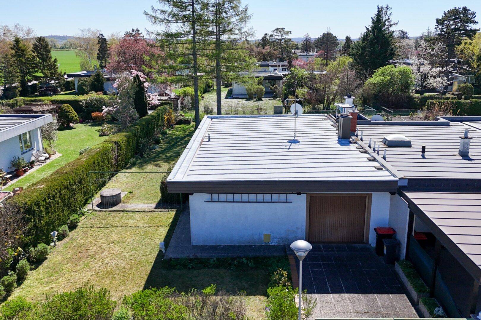 Draufsicht auf das Haus mit Flachdach, Garage und gepflegtem Gartenbereich.