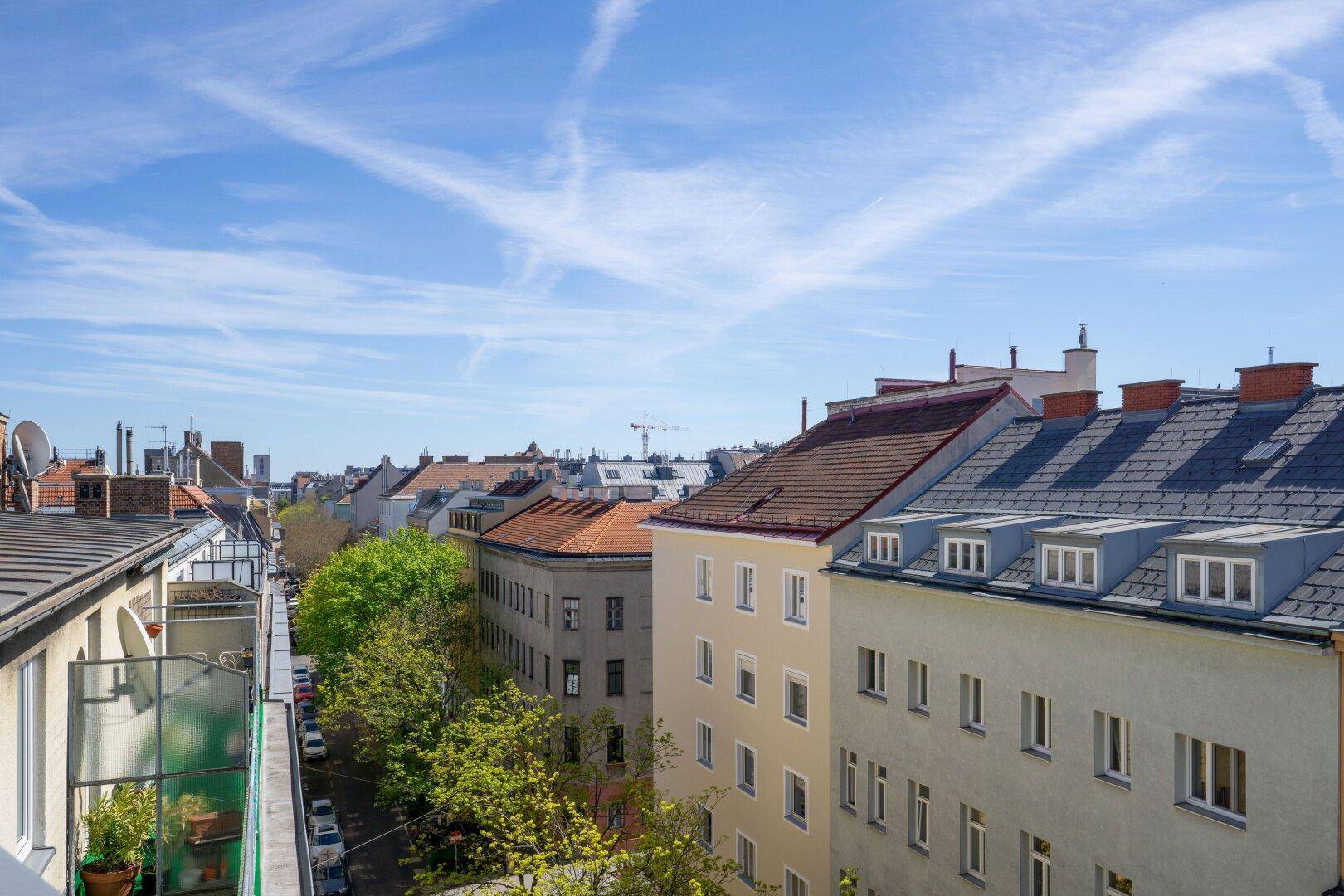 Weitläufiger Blick über die Dächer der Stadt mit grünen Bäumen und Wohngebäuden.