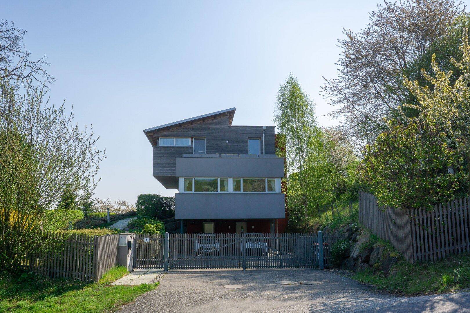 Ansicht des modernen Hauses von der Straße mit Holzelementen und einem Eingangstor.