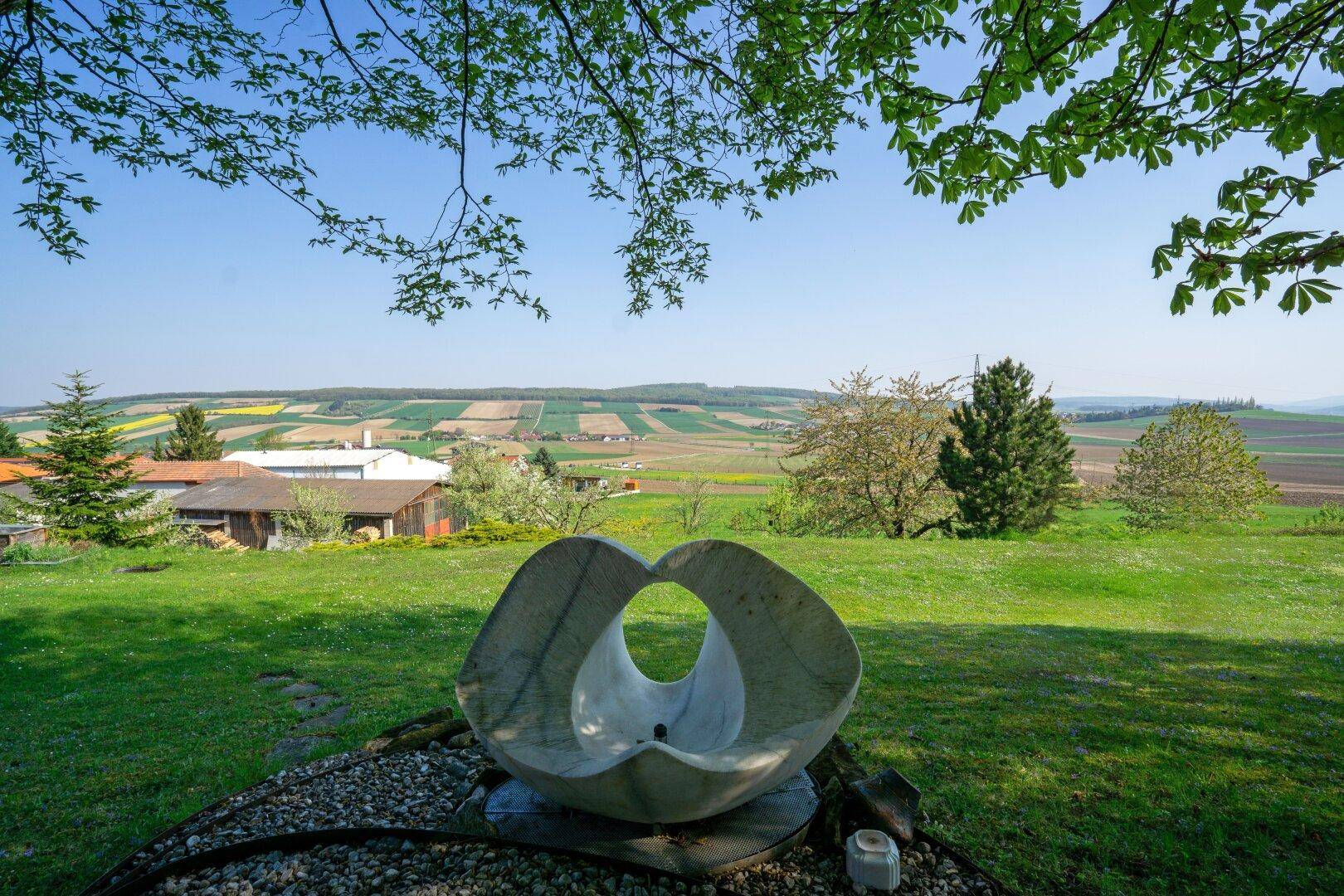 Skulptur im Garten mit Panoramablick über die Felder und die weite Landschaft.