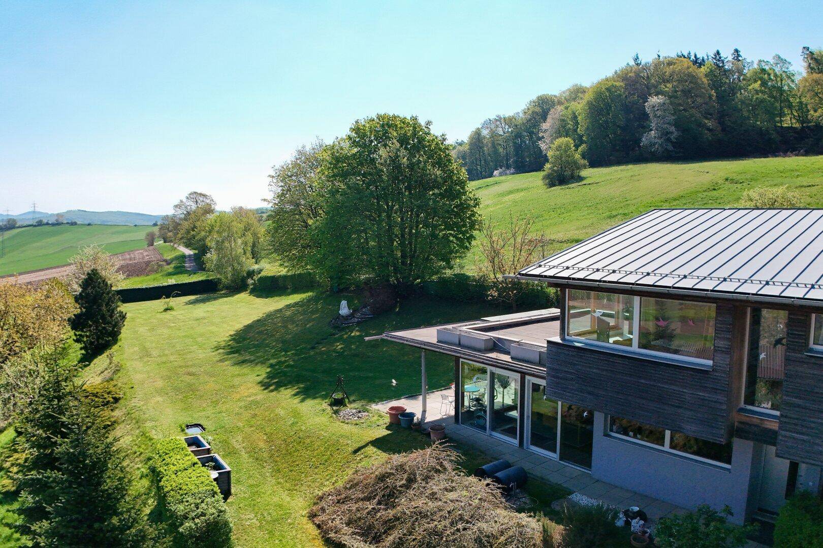 Weitläufiger Gartenbereich mit Rasenflächen und Blick auf die umliegende grüne Landschaft.