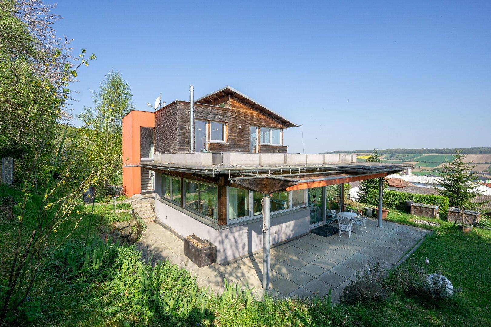 Große gepflasterte Terrasse am Haus mit Gartenmöbeln und weitem Blick ins Grüne.