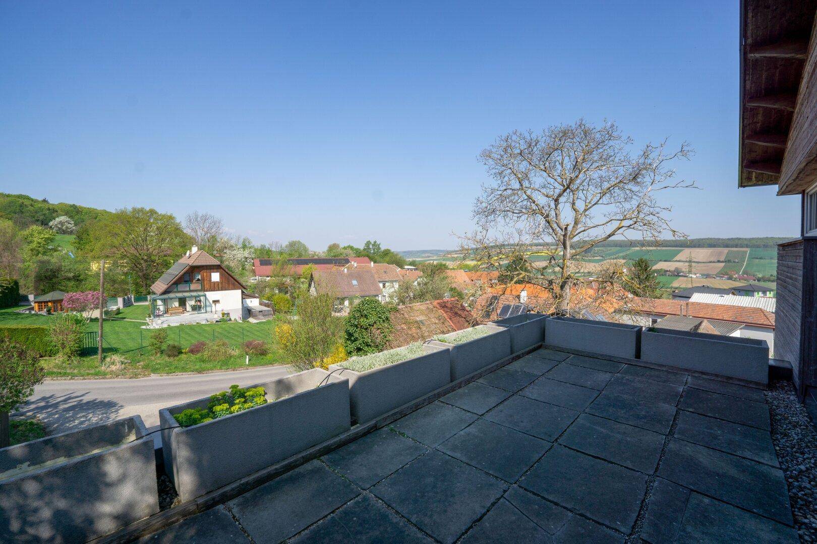 Geräumige Dachterrasse mit Fliesenboden und weitem Blick über die Landschaft und Nachbarhäuser.