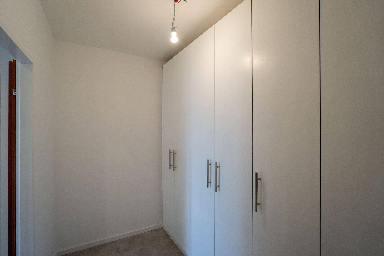 Kleiner Raum mit weißen Einbauschränken, ideal als Ankleidezimmer oder Abstellraum.