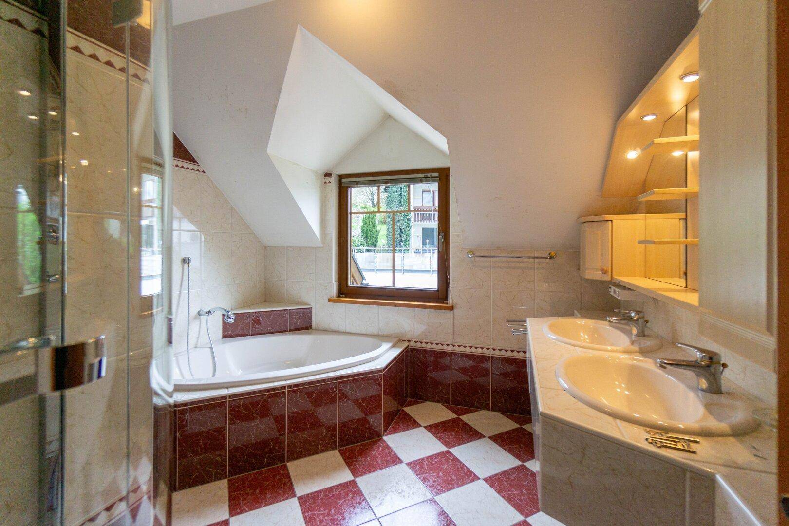 Badezimmer mit Eckbadewanne, Dusche und Doppelwaschbecken unter der Dachschräge.