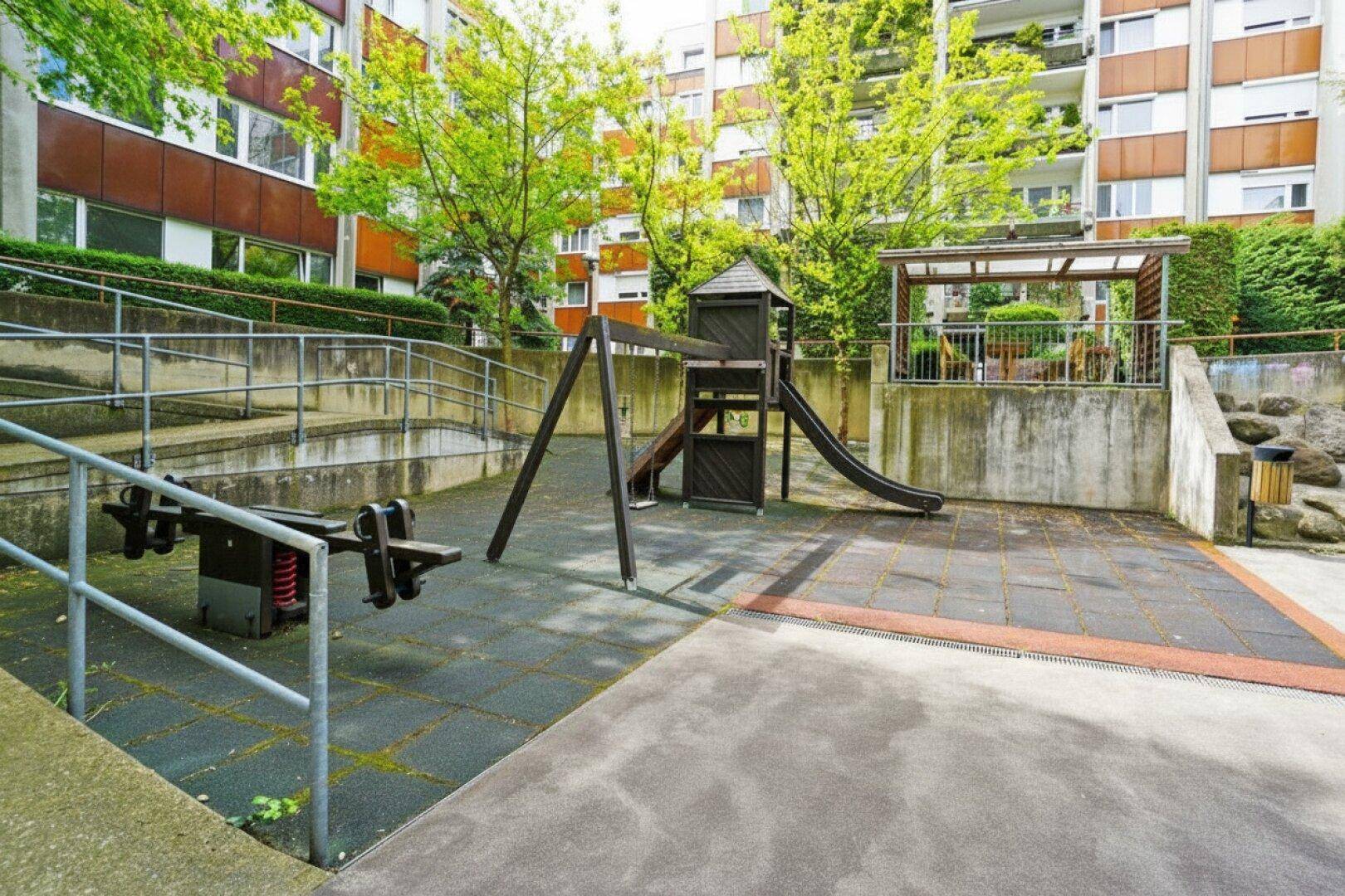 Kinderspielplatz mit Rutsche und Schaukeln im gemeinschaftlichen Bereich der Wohnanlage.