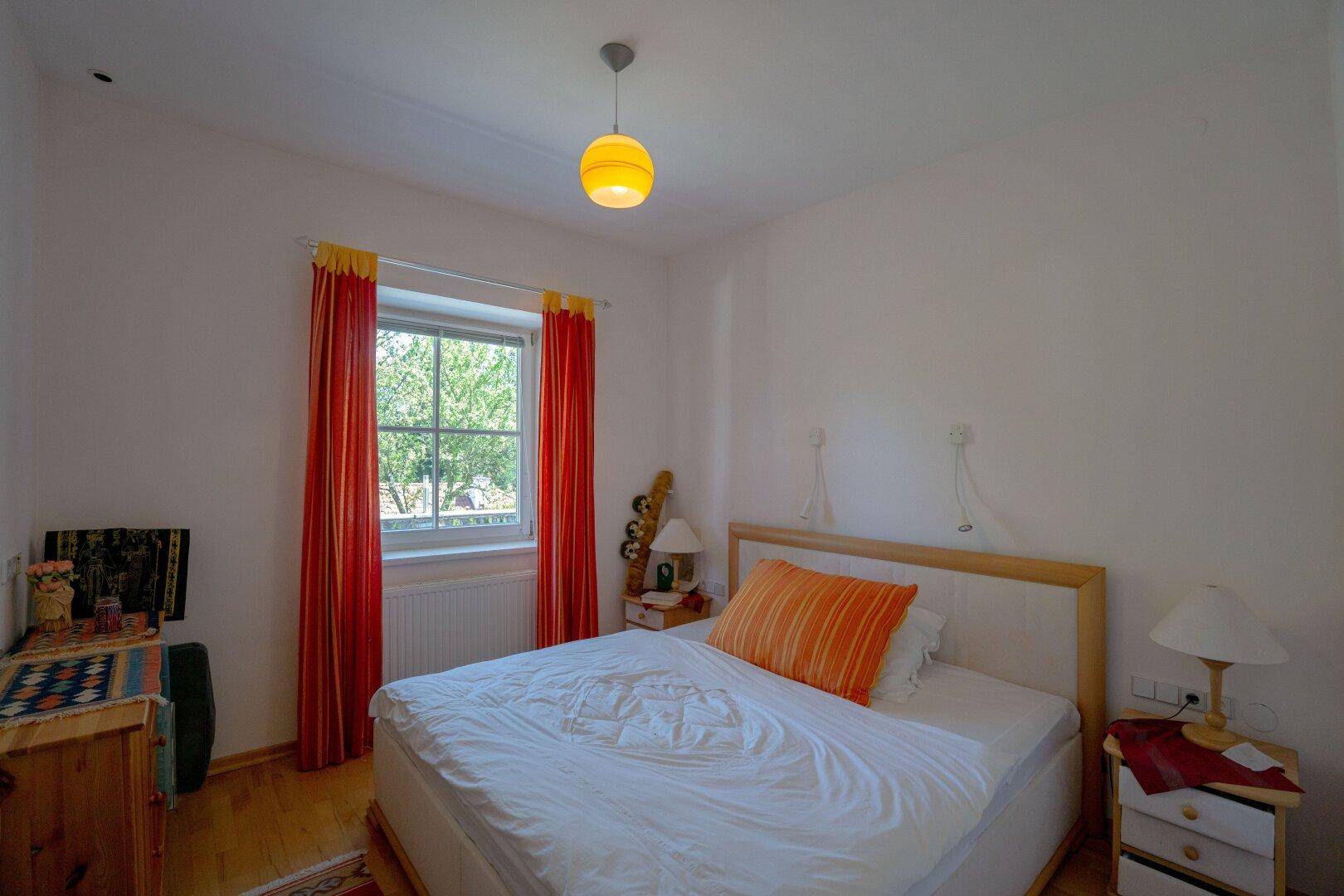 Gemütliches Schlafzimmer mit Doppelbett, Holzfußboden und Fenster zum Garten.